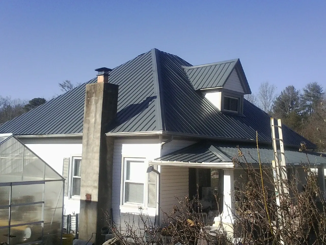 Dark blue standing seam metal roof on a white farmhouse with dormer — Slate & Tile Roof Repair by Roofing Brothers in Bow