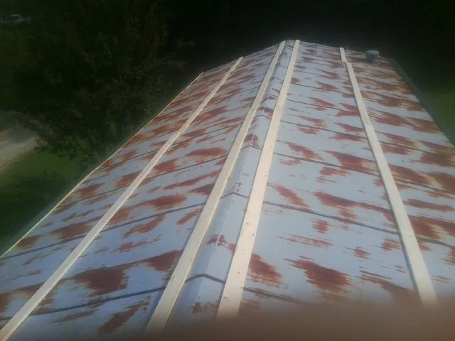 Rusted metal roof panels with new wood purlins before replacement — Storm Damage Roof Repair in Bow by Roofing Brothers