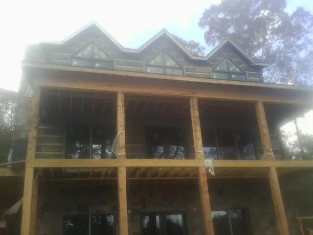Dormers and porch framing on a large log home under construction — Roof Coating work by our crew in Bow
